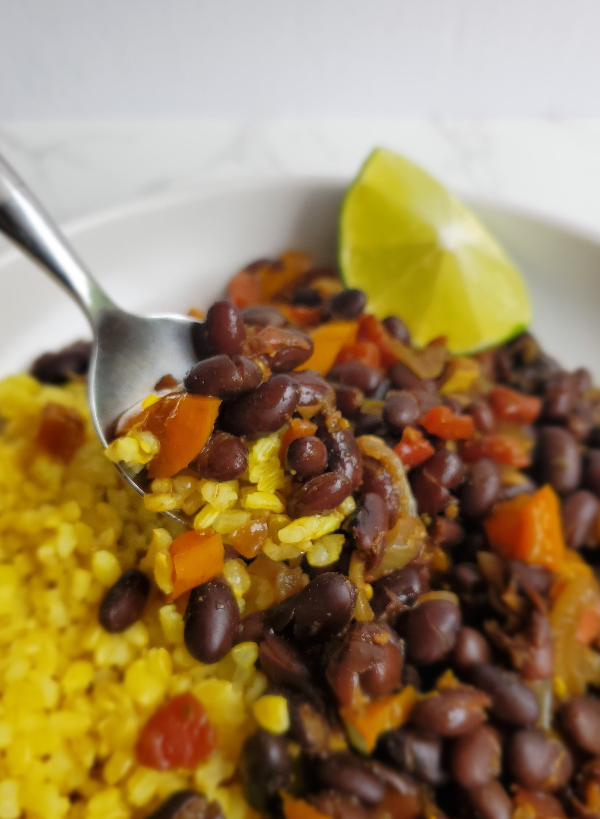 a spoon is scooping up tender black beans and rice