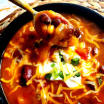 Pumpkin chili in a bowl topped with sour cream and cheese and green onion