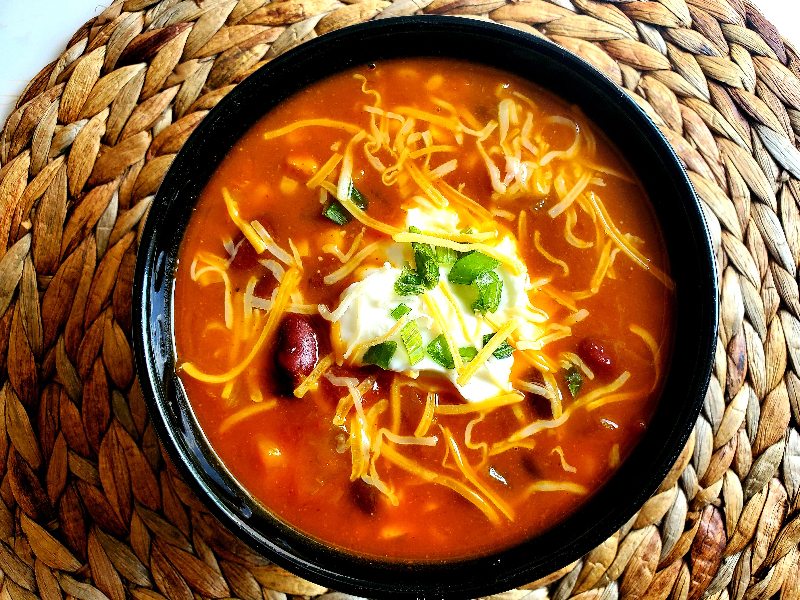 pumpkin chili topped with sour cream, green onion, and cheese