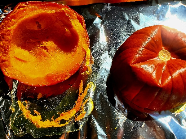 two roasted pumpkin halves showing soft pumpkin flesh and darker skin