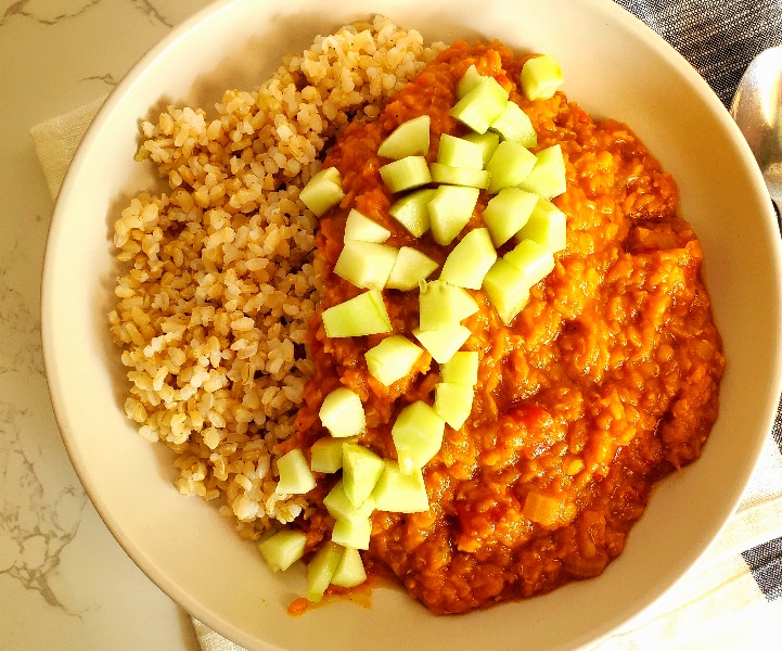 Creamy red lentils served over rice topped with diced cucumber