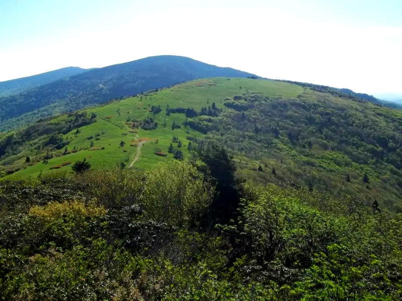 a distant trail leading up the bald summit of a mountain