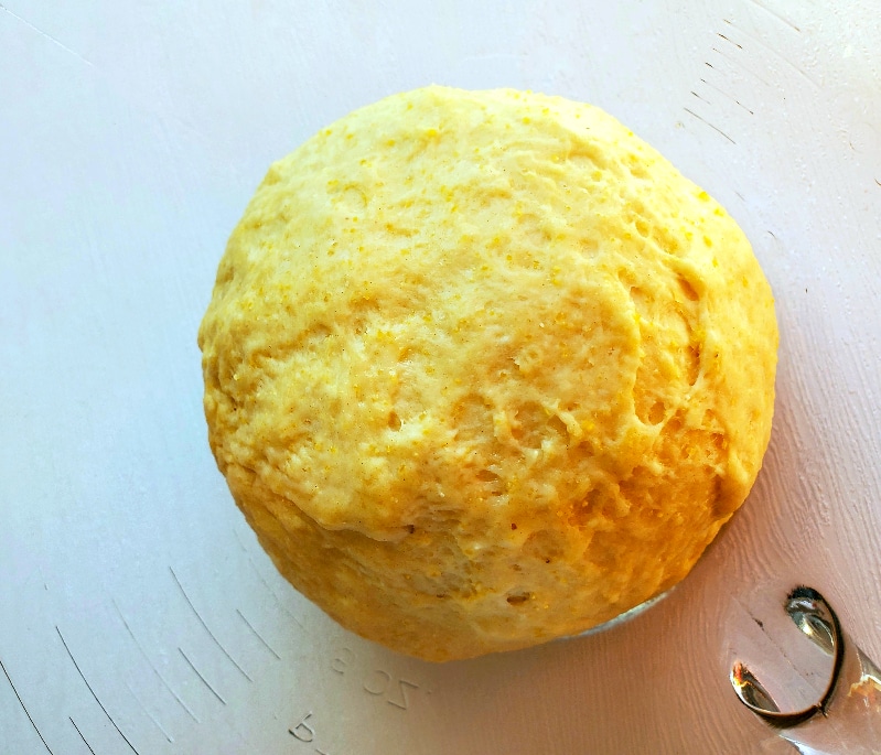 Deep dish pizza dough resting in oiled glass bowl to rise