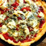 The Best Deep Dish Pizza hot out of the oven in a cast iron skillet and topped with blue cheese and ricotta