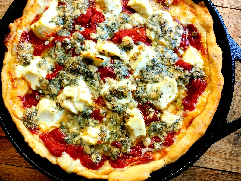 The Best Deep Dish Pizza hot out of the oven in a cast iron skillet and topped with blue cheese and ricotta