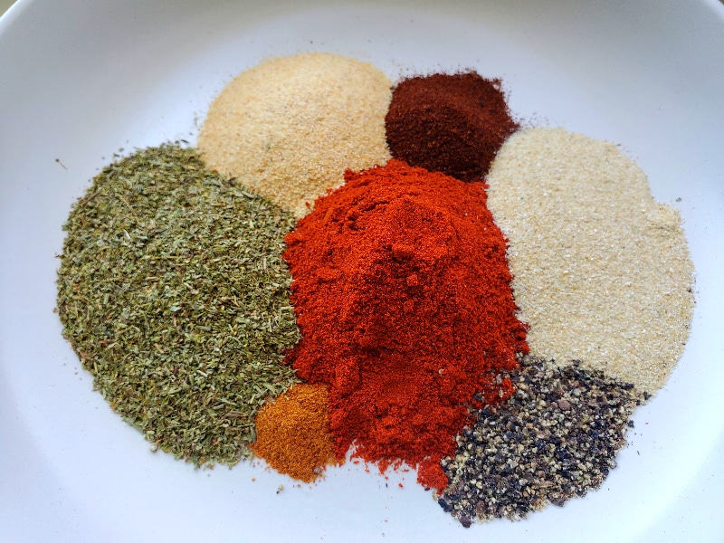 Spices and herbs on a plate waiting to be blended and made into creole seasoning