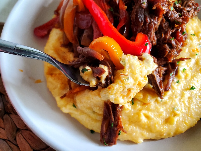 Mexican Shredded Beef on top of Cheese Grits with sauteed peppers and onions