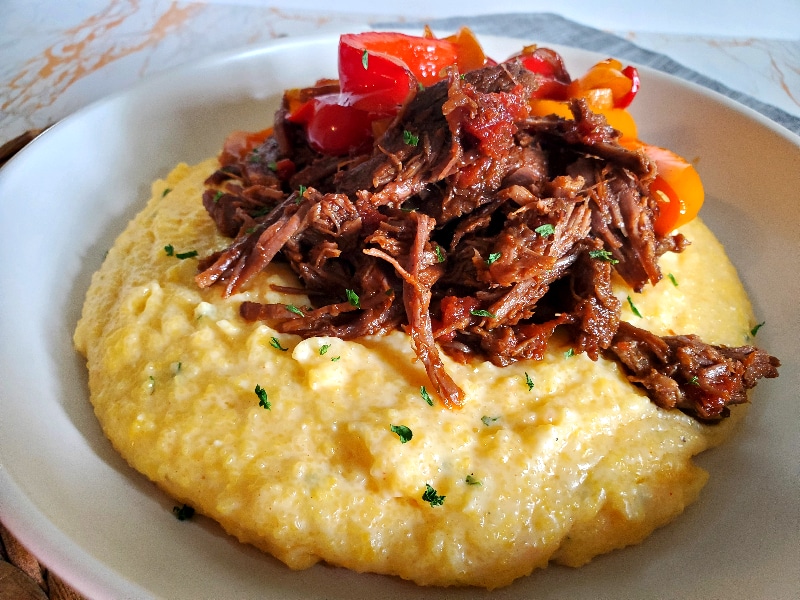 Mexican Shredded Beef on top of Cheese Grits with sauteed peppers and onions