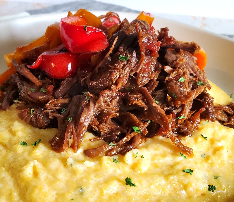 Mexican Shredded Beef on top of Cheese Grits with sauteed peppers and onions