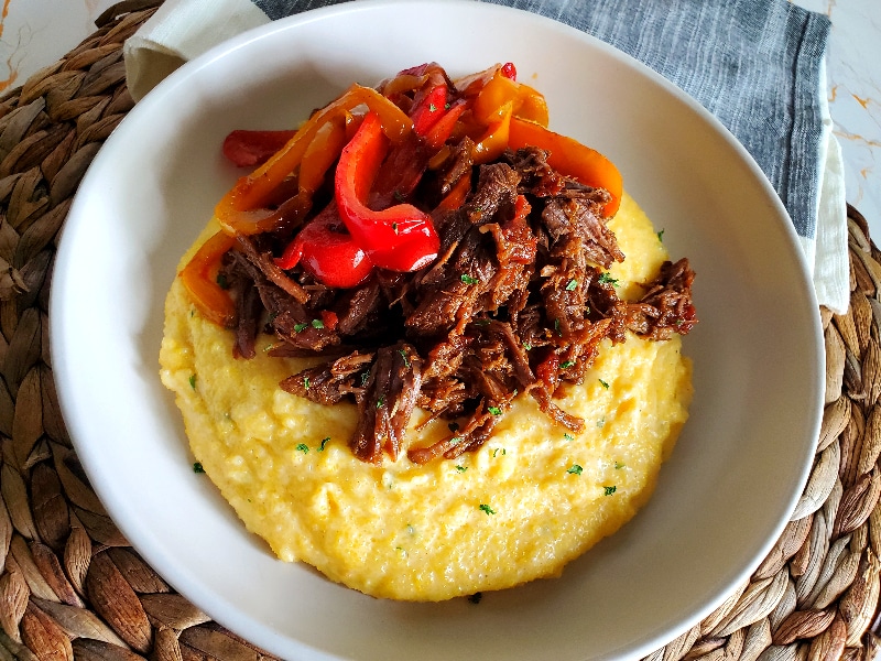 Mexican Shredded Beef on top of Cheese Grits with sauteed peppers and onions