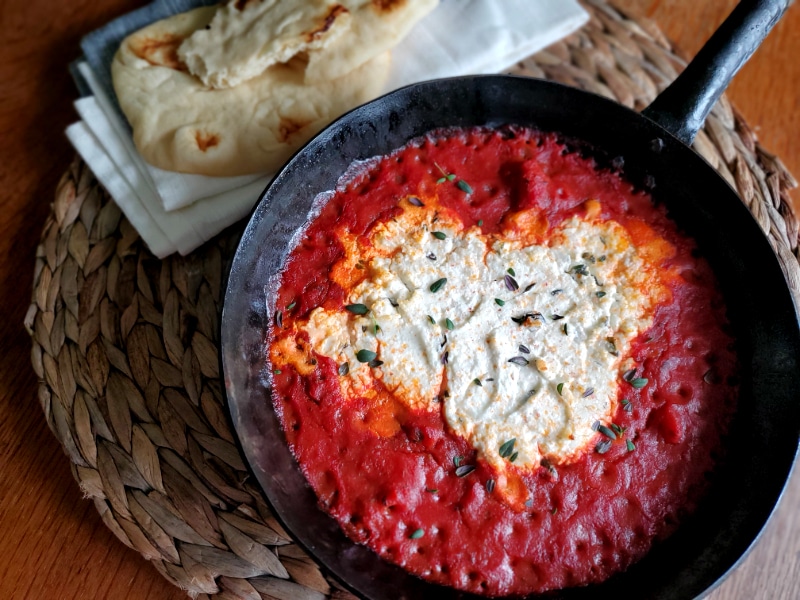 Creamy goat cheese surrounded by marinara sauce 