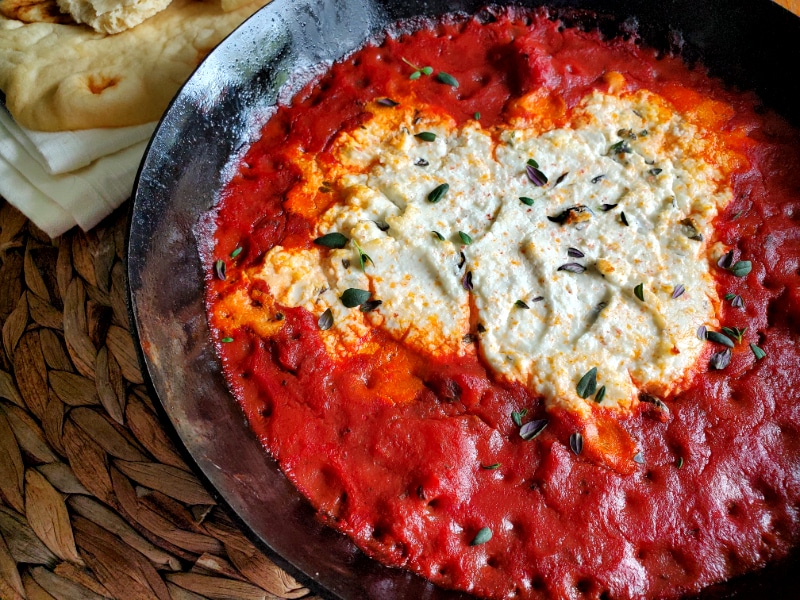 Creamy goat cheese surrounded by marinara sauce 