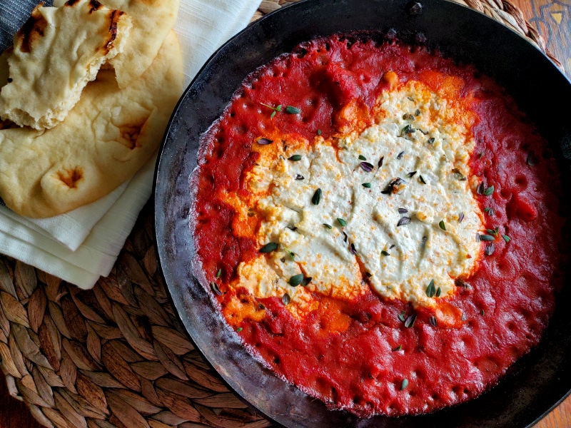 Creamy goat cheese surrounded by marinara sauce 